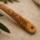 Close-up of a sample family name engraved on an olive wood ladle handle with a hanging hole