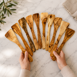 Hands fanning out a set of olive wood spatulas showing the different grain on each one