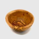 Olive wood pinch bowl on a gray background showing the swirling grain inside