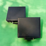 Two plain black leather 100 chip poker set cases on green felt, ready for engraving