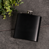 Matte black powder coated flask with screw cap on dark stone, blank for a personalized groomsmen gift