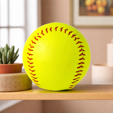 Plain yellow softball displayed on a wooden shelf with a plant, ready for a custom name keepsake