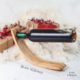 Olive wood balancing wine bottle holder with dimensions marked, about 26 cm long and 6 cm wide