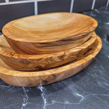 Set of three olive wood serving trays nested together on a dark marble counter