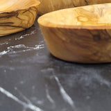 Two oval olive wood serving dishes from a low angle on a black marble counter