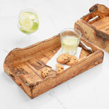 Rustic olive wood serving tray with natural edge handles holding cookies and drinks on marble