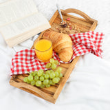Breakfast in bed on a handmade olive wood serving tray with juice, croissant and grapes