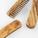 Close-up of olive wood beard comb teeth and a handle engraved with a small sample logo