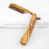 Olive wood folding beard comb opened at a right angle on a white towel, personalized grooming gift