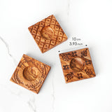 Three olive wood ravioli molds in different carved patterns with size marked at about 10 cm square