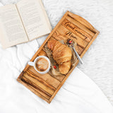 Handmade olive wood serving tray engraved with a sample message, holding coffee and a croissant on a bed