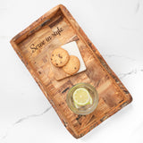 Handmade olive wood serving tray engraved with a sample phrase, holding cookies and lemon water