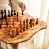 Olive wood chess table with red and natural squares, hand moving a black piece