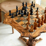 Close-up of a natural edge olive wood chess table top with dark squares and wooden pieces