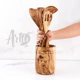 Hand placing olive wood cooking utensils into the matching olive wood holder
