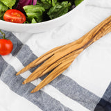 Close-up of two olive wood serving forks on a striped towel showing the natural wood grain