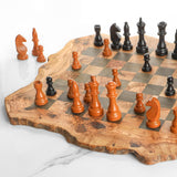 Rustic olive wood chess board with wooden pieces in play on white marble