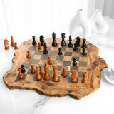 Olive wood chess board with dark squares and rough edges set up for a game on a white table