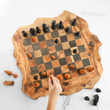 Top view of a live edge olive wood chess board with a hand reaching for a piece
