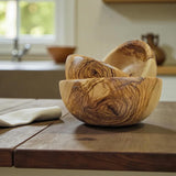 Round olive wood bowls nested together on a wooden kitchen table