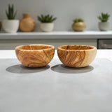 Pair of round olive wood bowls side by side on a gray counter, natural wooden snack bowls