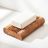 Handmade olive wood soap dish with drainage ridges holding a white bar of soap