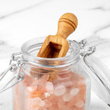 Olive wood spice scoop in a glass jar of pink Himalayan salt