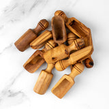 Pile of handmade olive wood spice scoops in multiple sizes on white marble