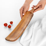 Hands lifting an empty long olive wood serving tray with a curved handle