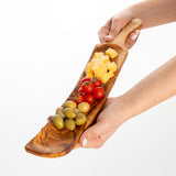 Hands holding a personalized-ready olive wood charcuterie board with olives, tomatoes and cheese