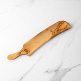 Empty handmade olive wood charcuterie board with handle on white marble showing the grain